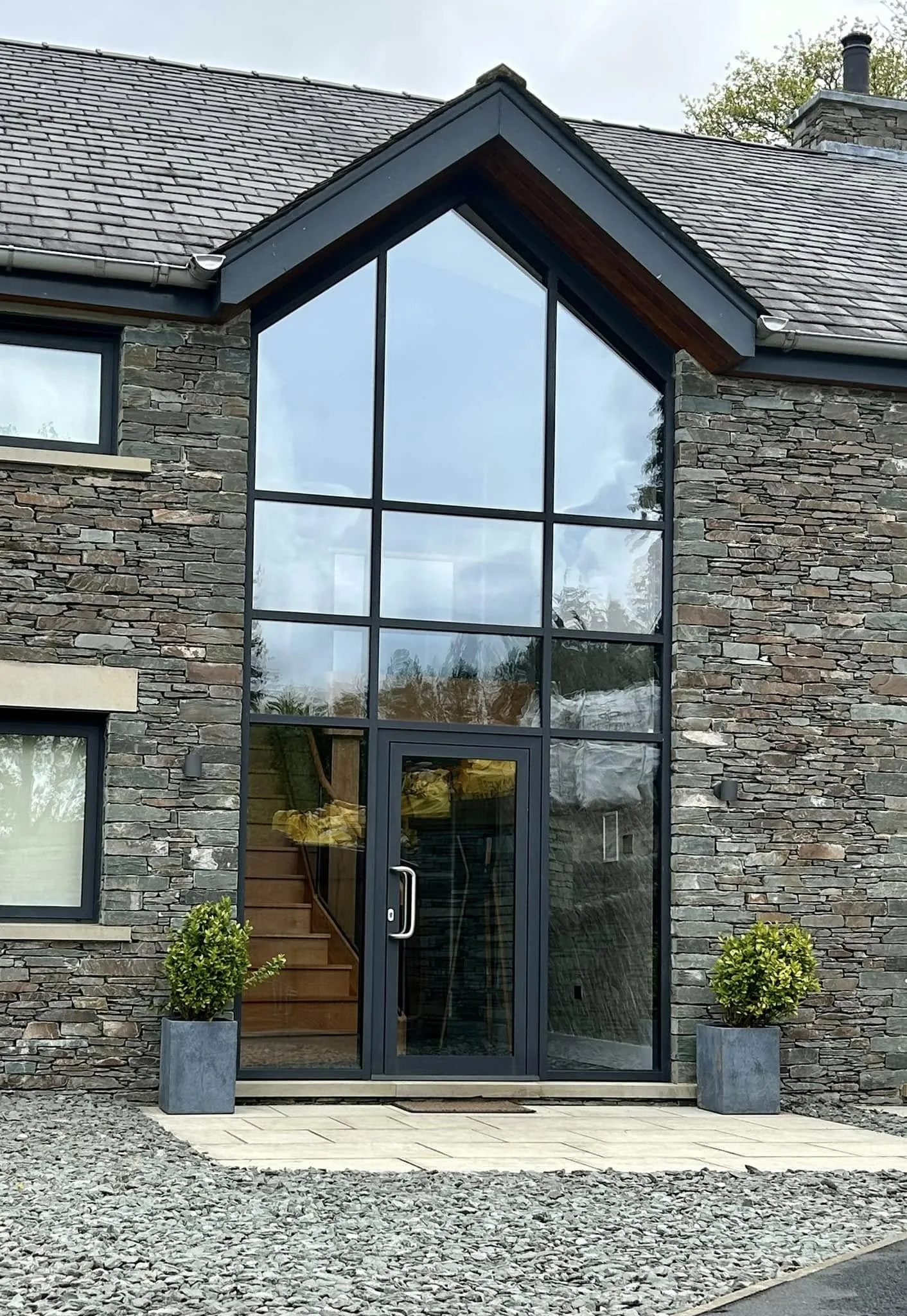 Aluminium-framed entrance and full-height gable glazing in a stone elevation